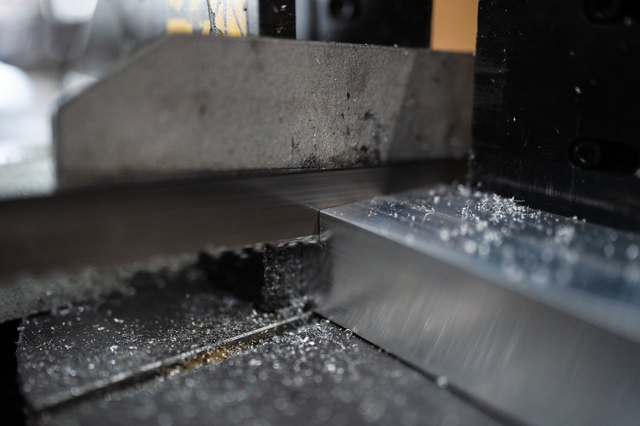 Metallbandsäge schneidet ein Stück Aluminium mit Spänen auf der Oberfläche.